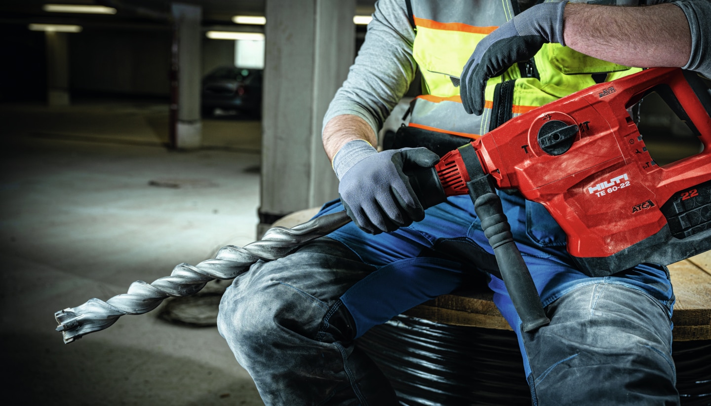 Construction worker sitting with a TE 60-22 Combihammer and a TE-YX hammer drill bit resting on his knee