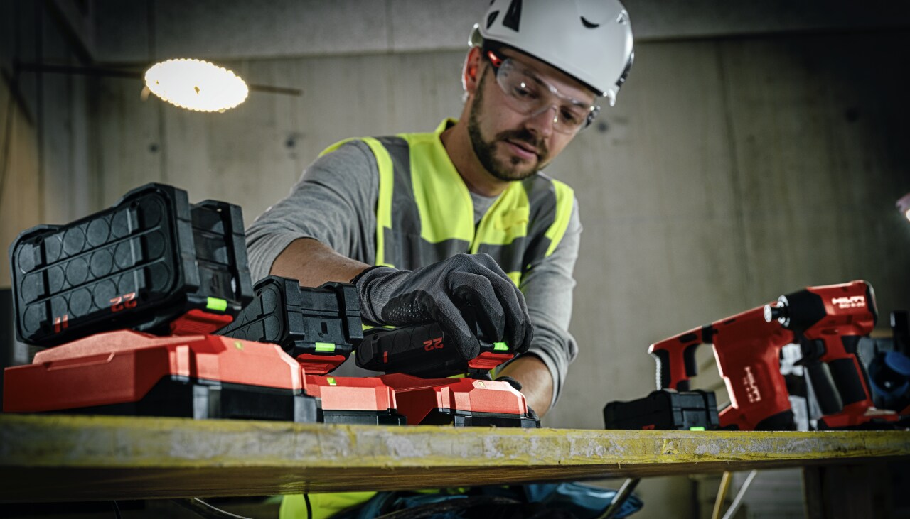 Mechanical Trade Worker (plumber) putting a Nuron battery on a charger, a TE 4-22, SID 6-22 and SL 2-22 are also in background